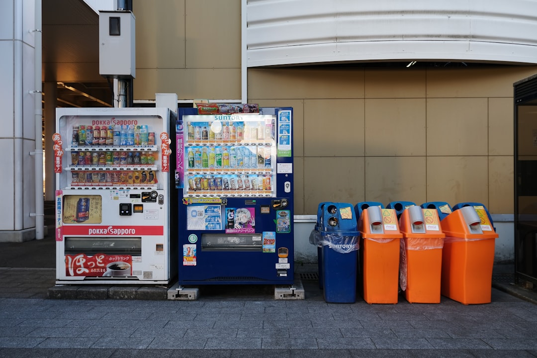 ：recycling bins for cans and bottles beside a vending machine in japan