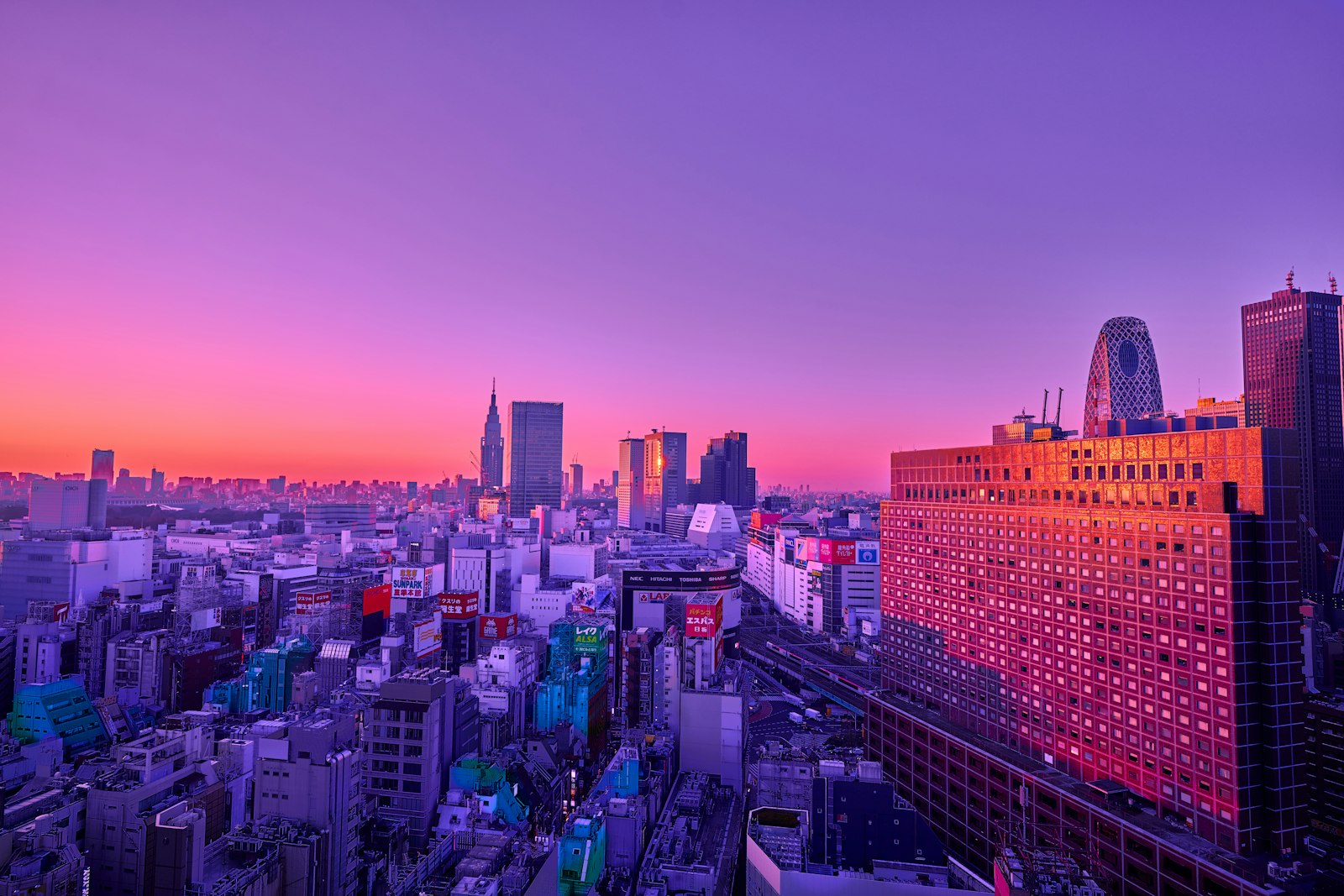 An aerial view of the Tokyo skyline under a vibrant purple and orange sky