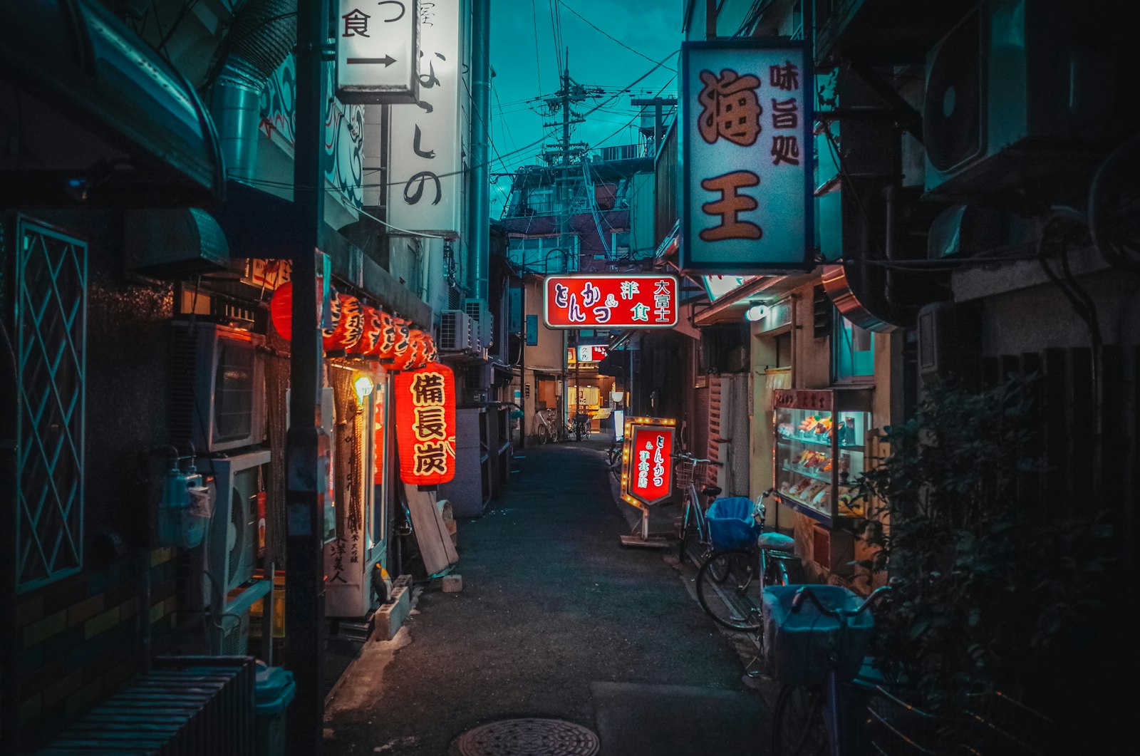 A narrow alleyway in Japan illuminated by glowing red and white neon signs