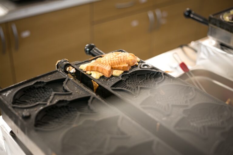 ：taiyaki fish shaped cakes cooking in cast iron moulds