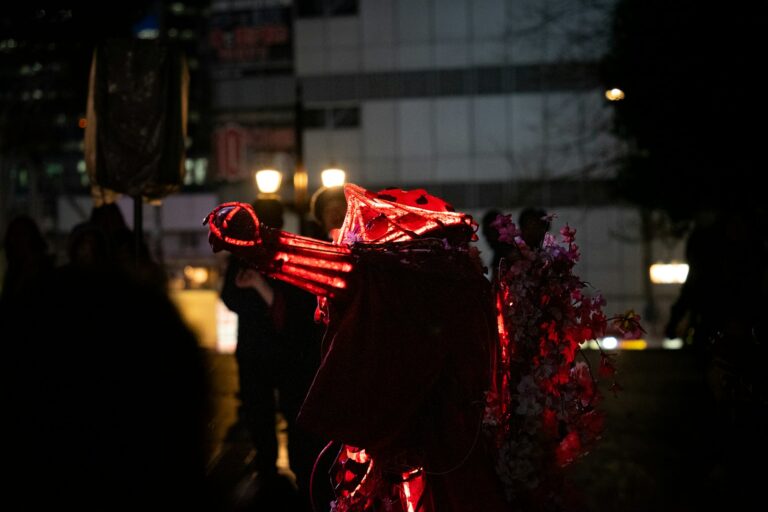 People in costumes with glowing red lights at night