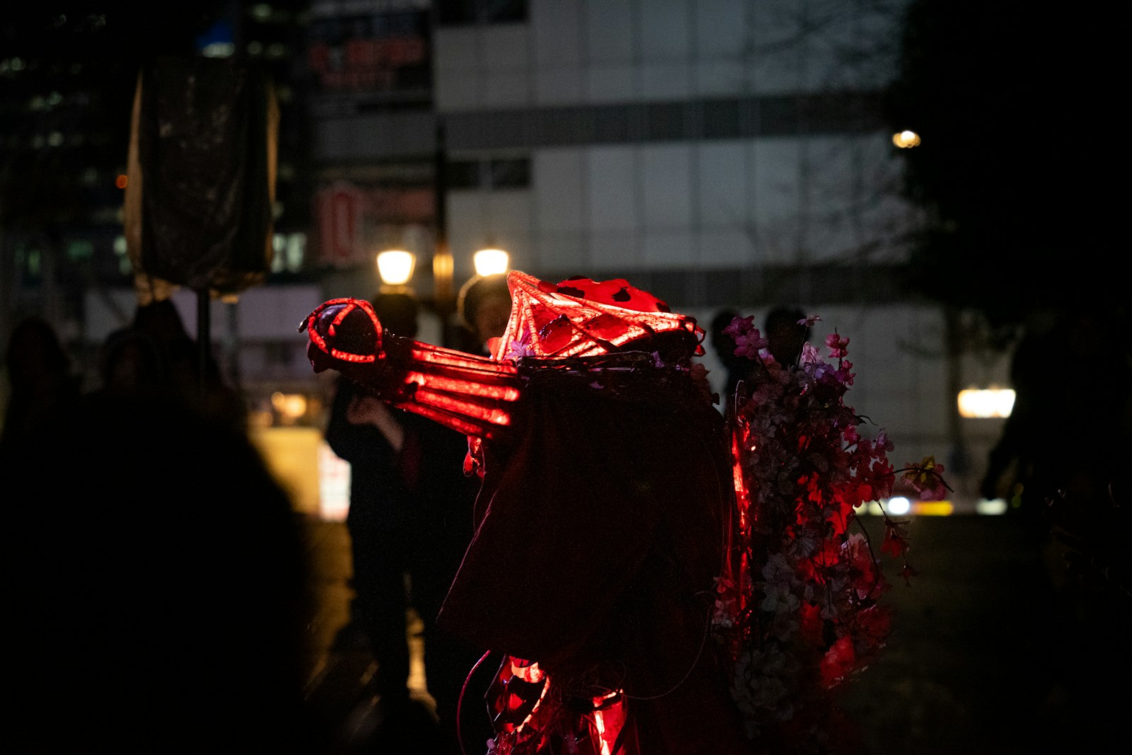 People in costumes with glowing red lights at night