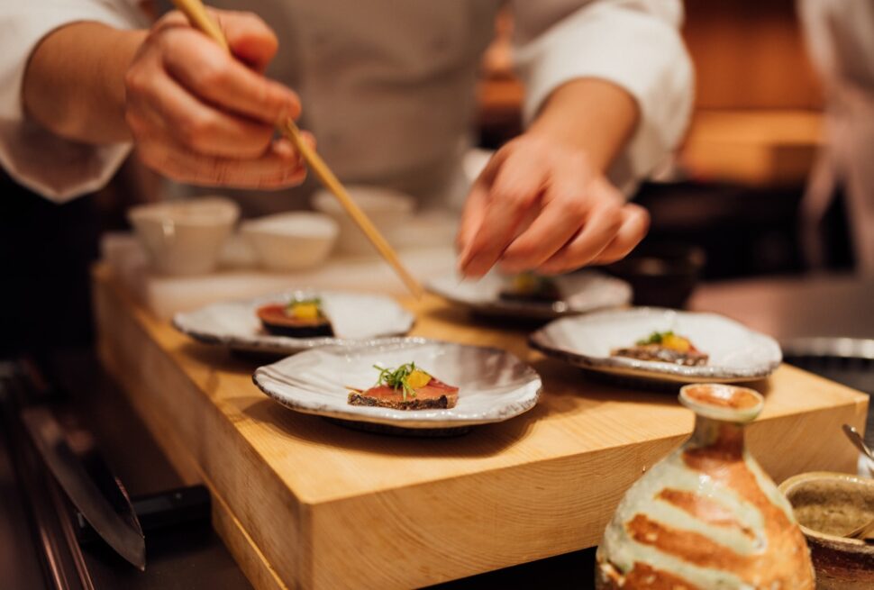 a person holding a chopstick over a plate of food