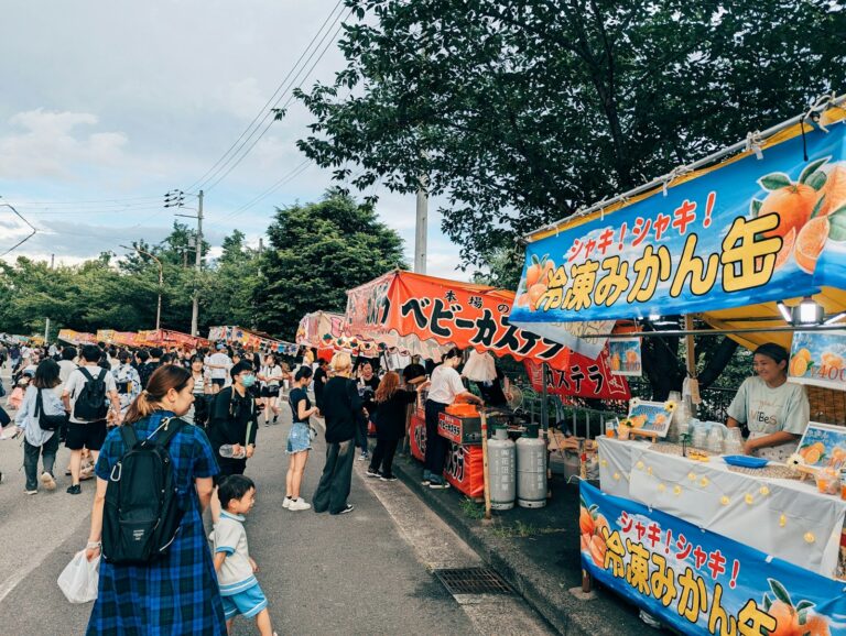 A group of people walking down a street next to a food cart