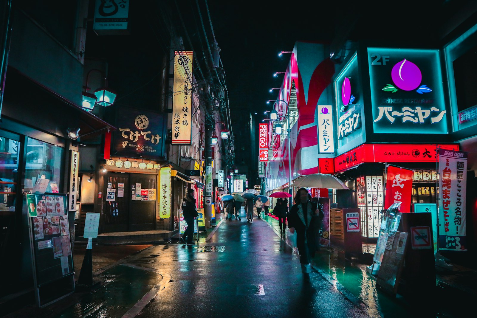 a group of people walking down a street at night