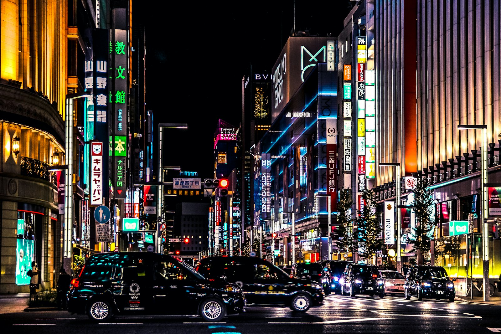 cars on road between high rise buildings during night time