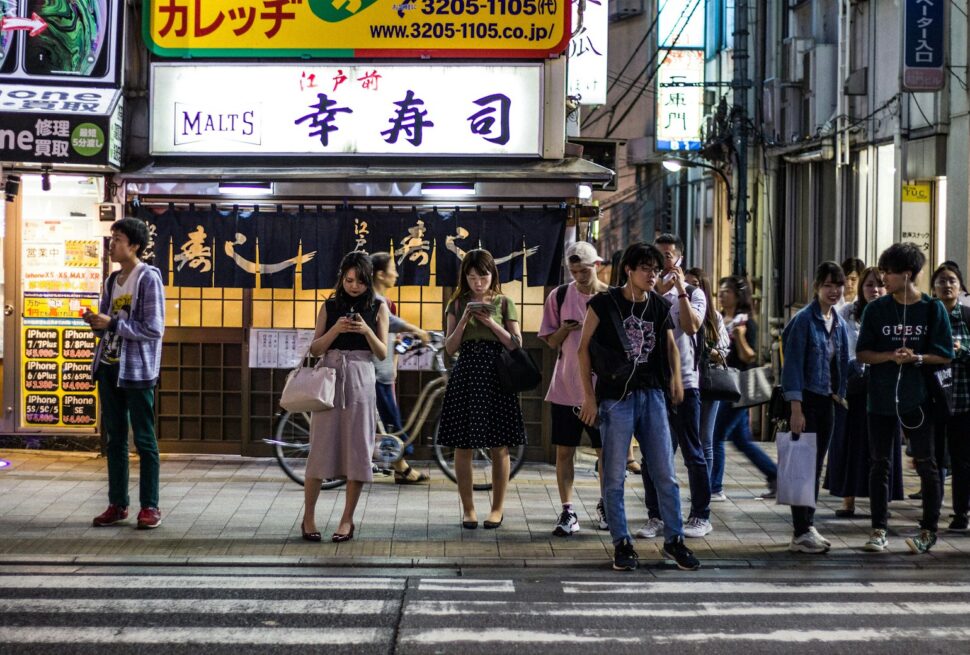 people standing near road beside buildings during night time
