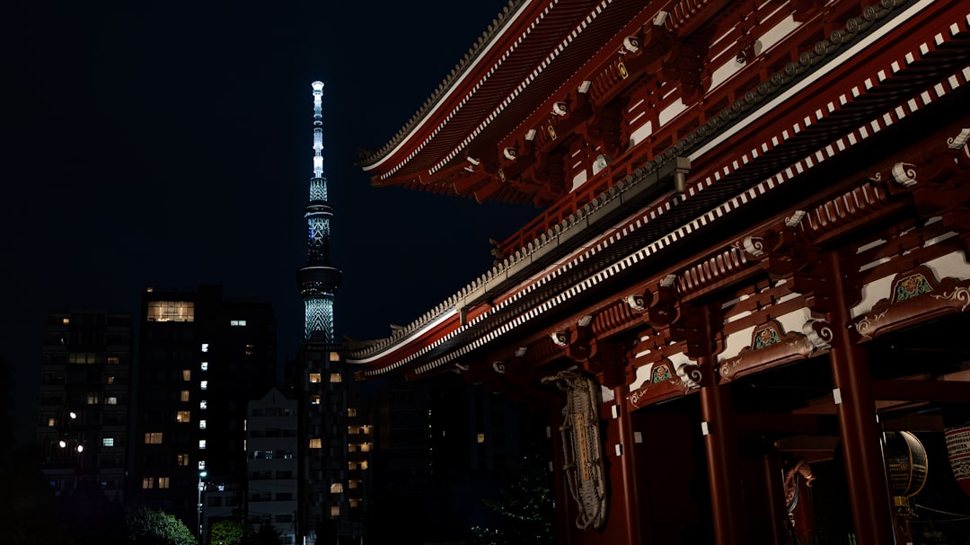 ：zojoji temple with tokyo tower lit up behind at night